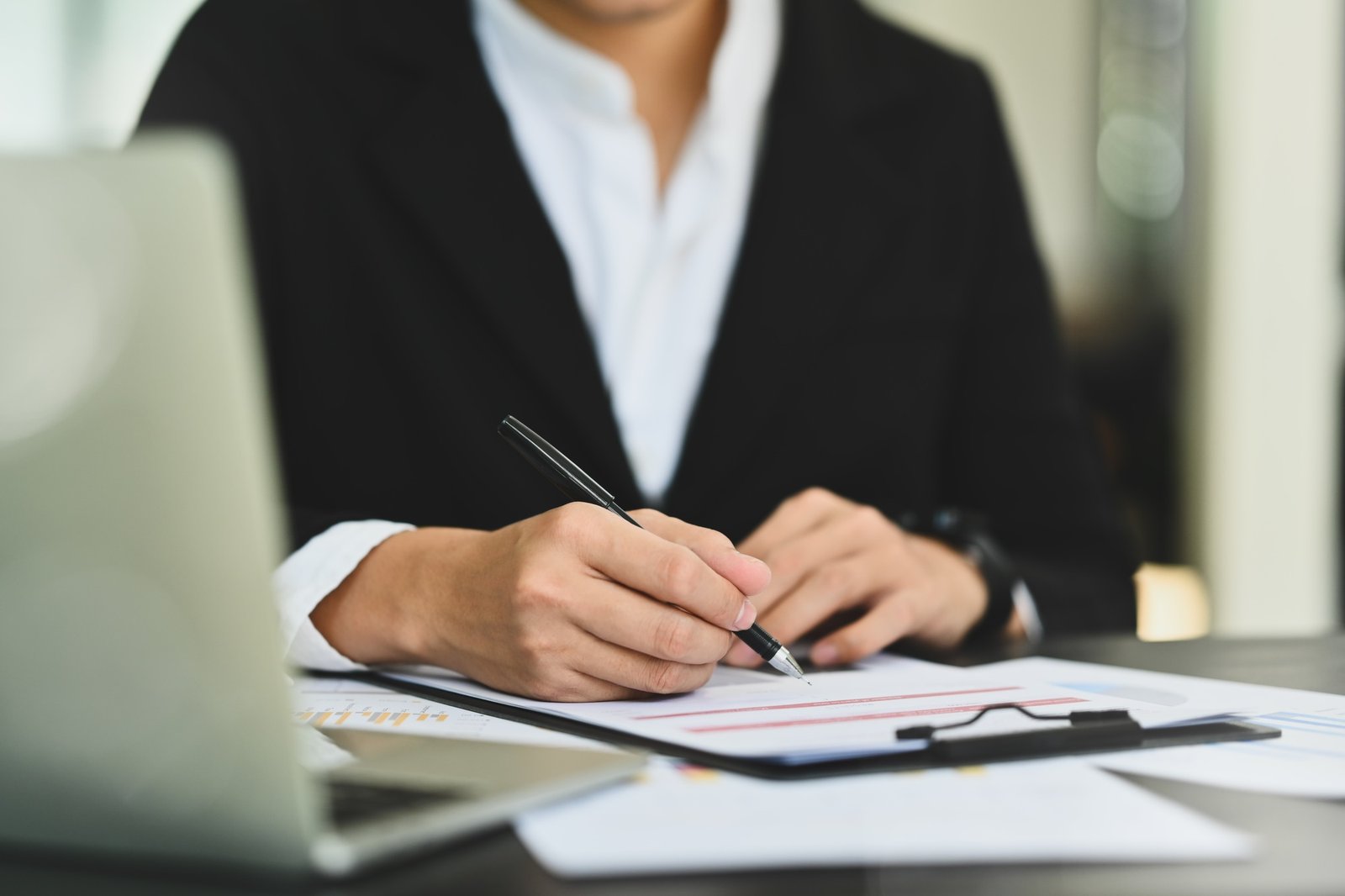 Businessman in formalwear putting personal signature on contract document at desk