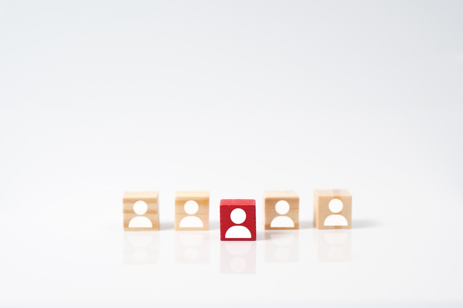 Focus red human icon on wooden block, choice of employee leader from the crowd.