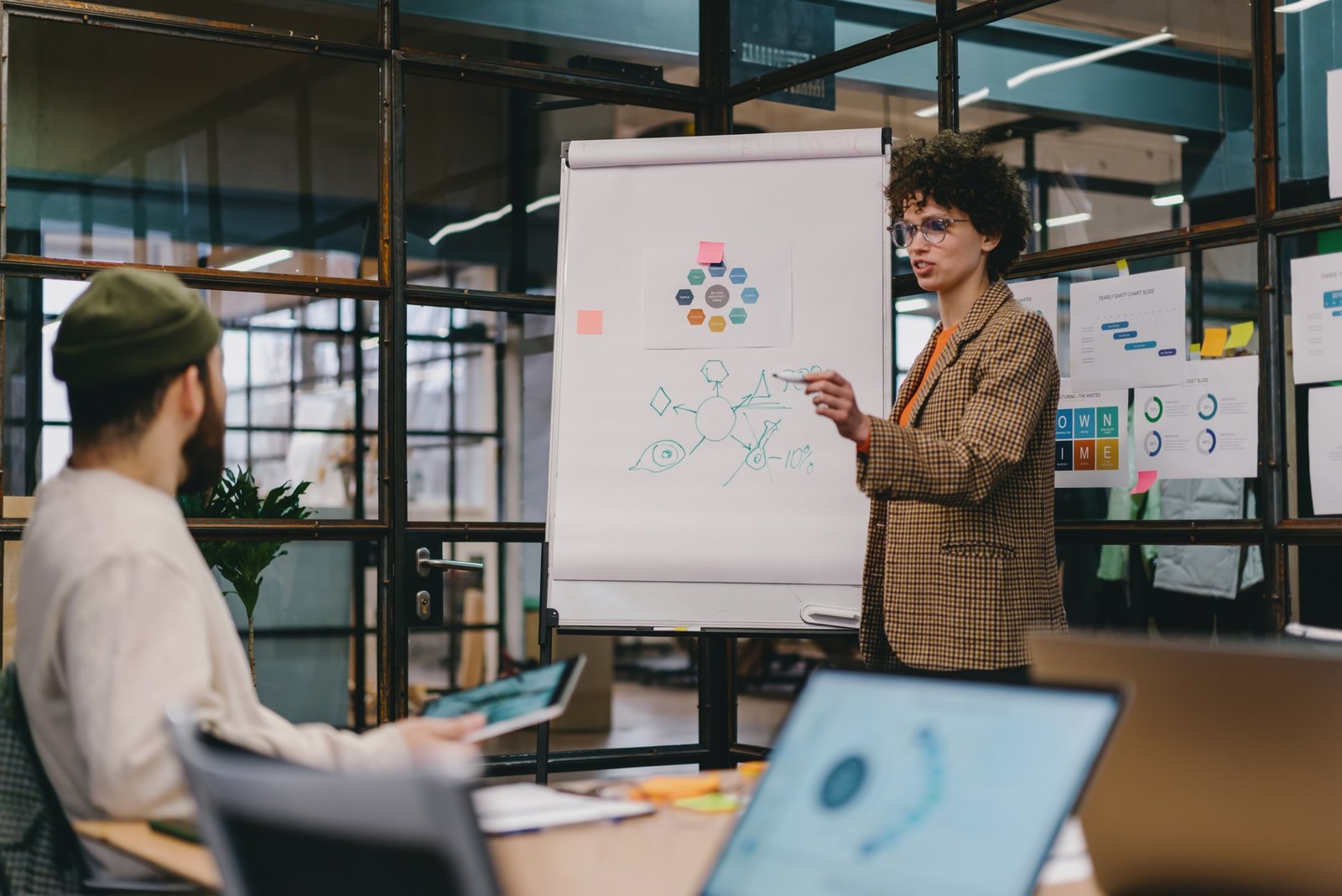 Focused young woman explaining project with chart on board to colleague