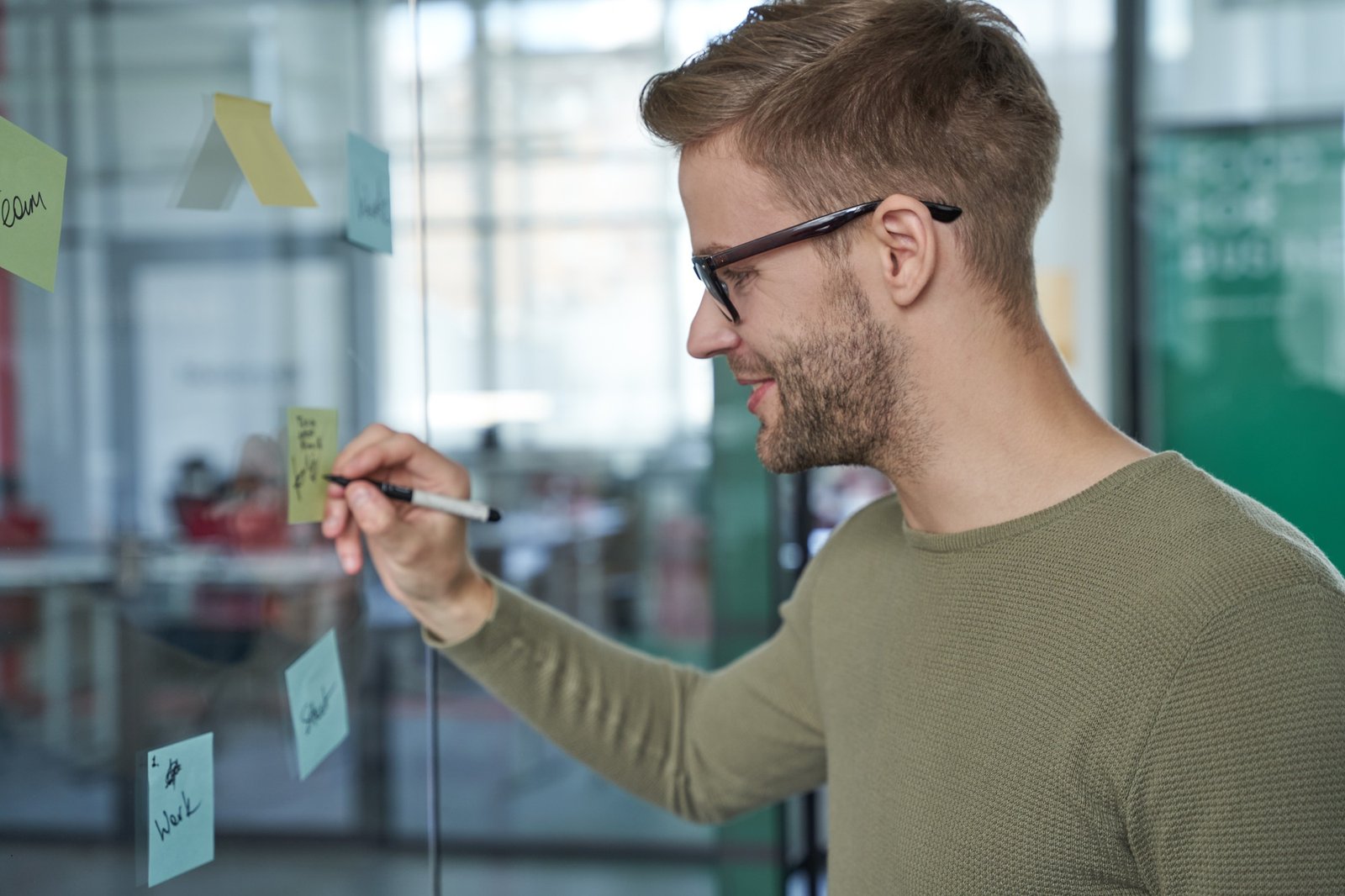 Happy worker writing notices of meeting on board