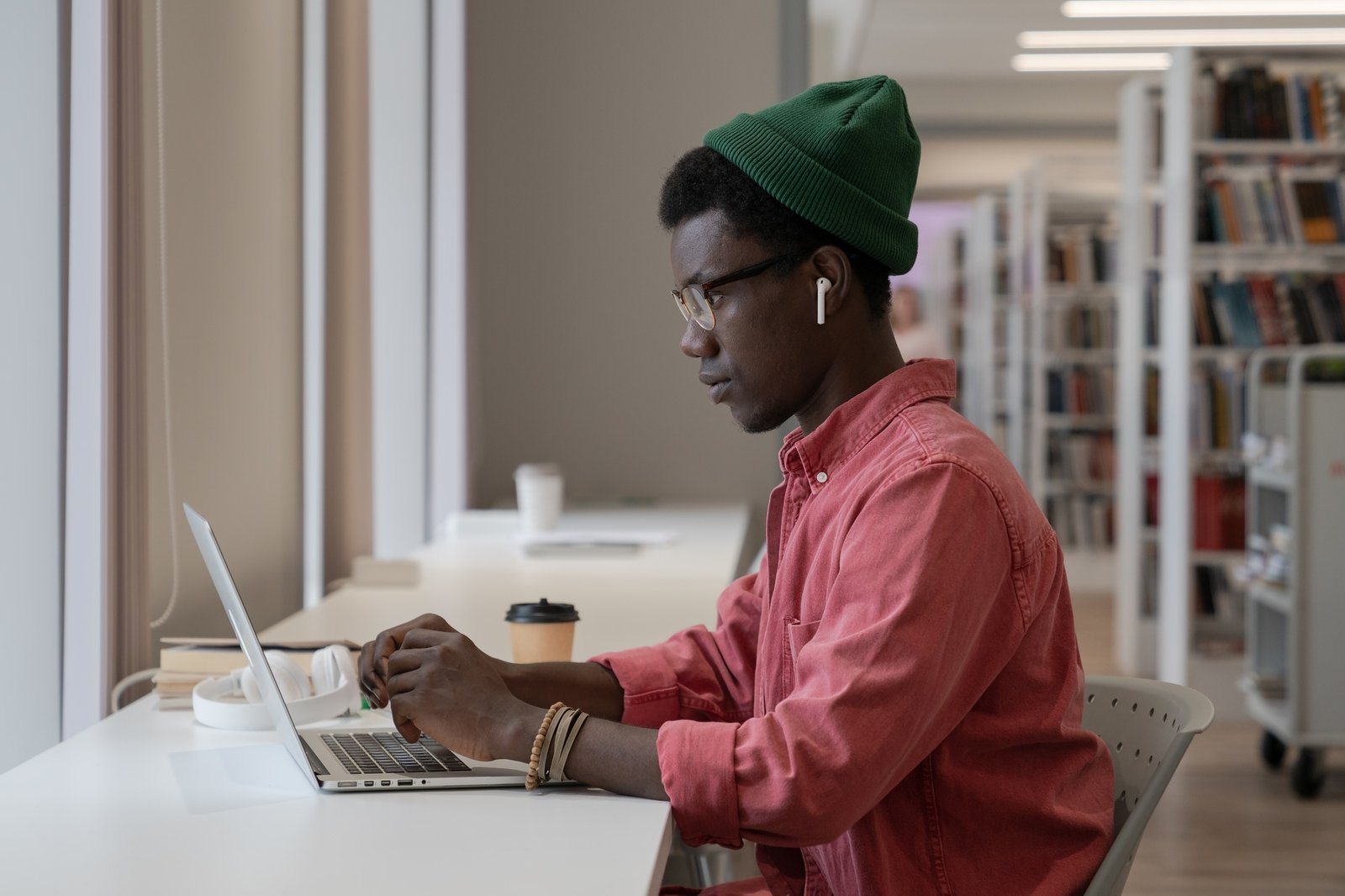Pondered black intern man employee look at laptop screen typing text or browsing web for education.