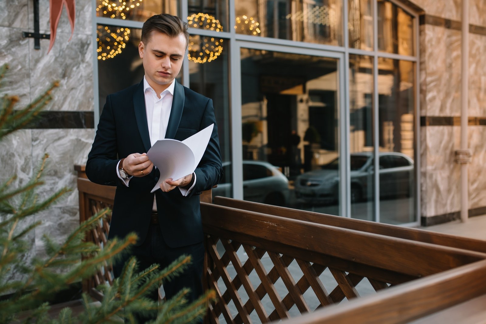 Young business man with documents and mobile phone near of modern building.
